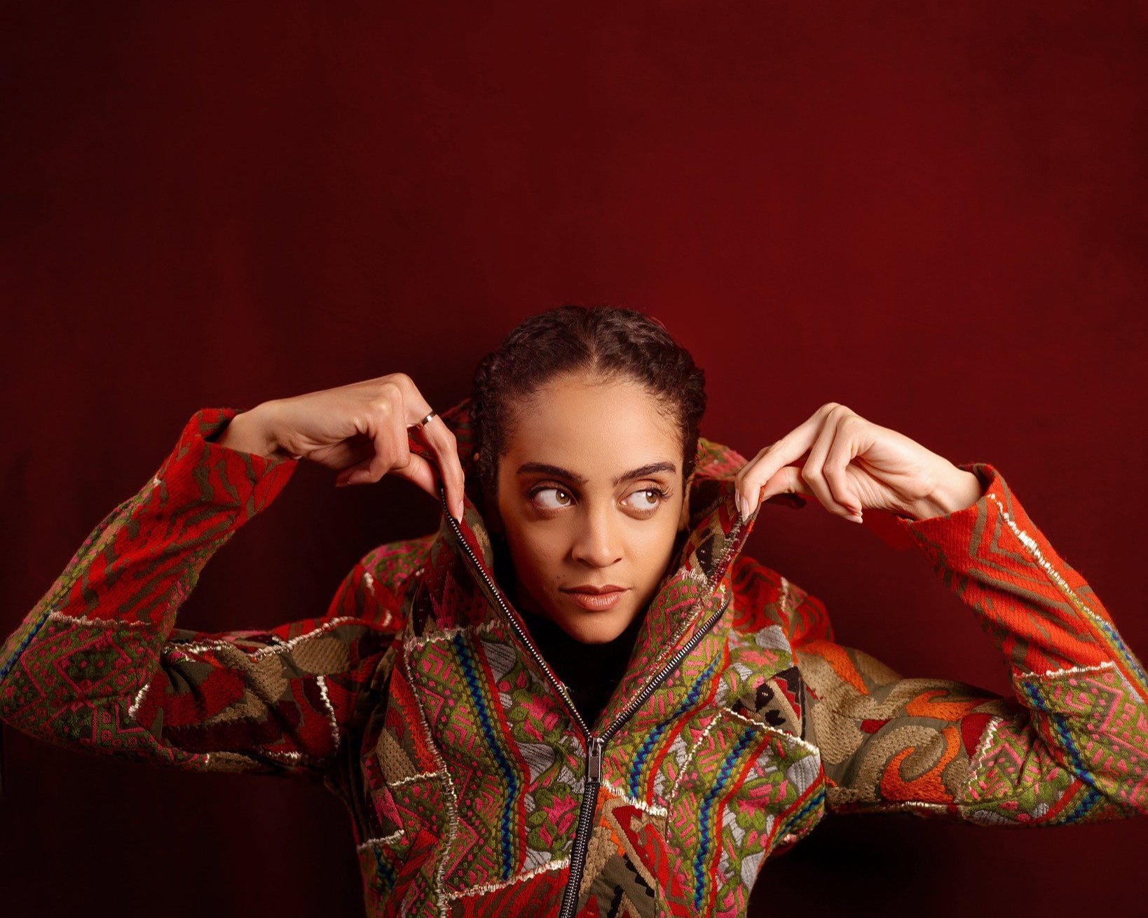 Woman with dark curly hair in a colorful patterned jacket